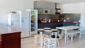 A modern kitchen with white appliances, a dining table with chairs, and a red countertop. - ARCA NOVA GUEST HOUSE & HOSTEL (Caminha)