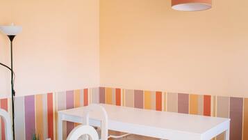 A dining area with a white table and chairs, a hanging lamp, and a striped wall.