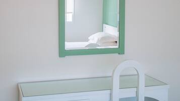 A white vanity with a mirror and a chair.
