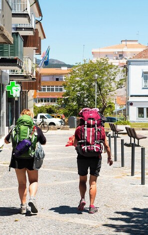 Two individuals walking on a cobblestone street, each carrying a backpack. - ARCA NOVA GUEST HOUSE & HOSTEL (Caminha)