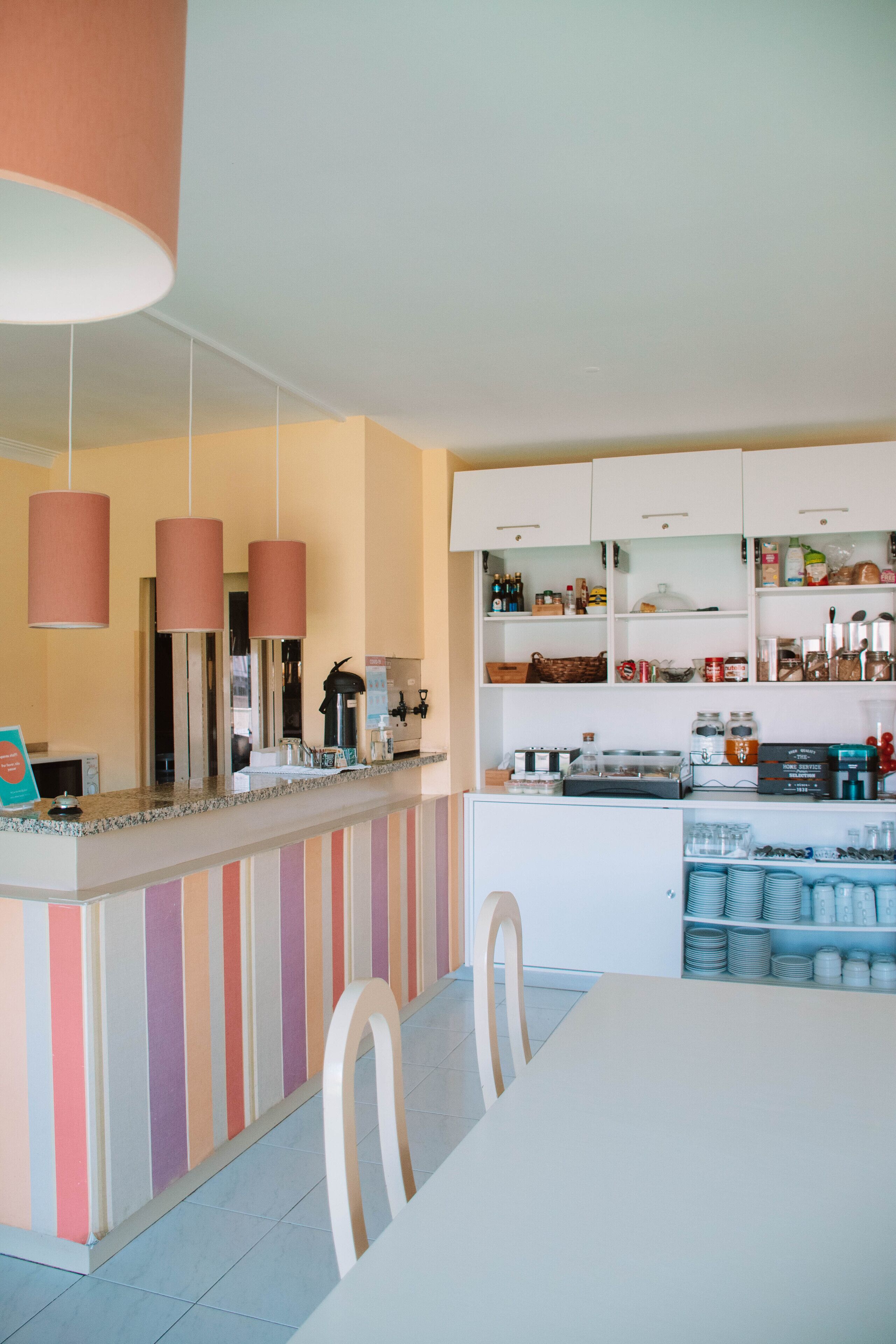 Uma cozinha moderna com paredes listradas, uma ilha central com uma máquina de café e uma área de jantar com cadeiras.