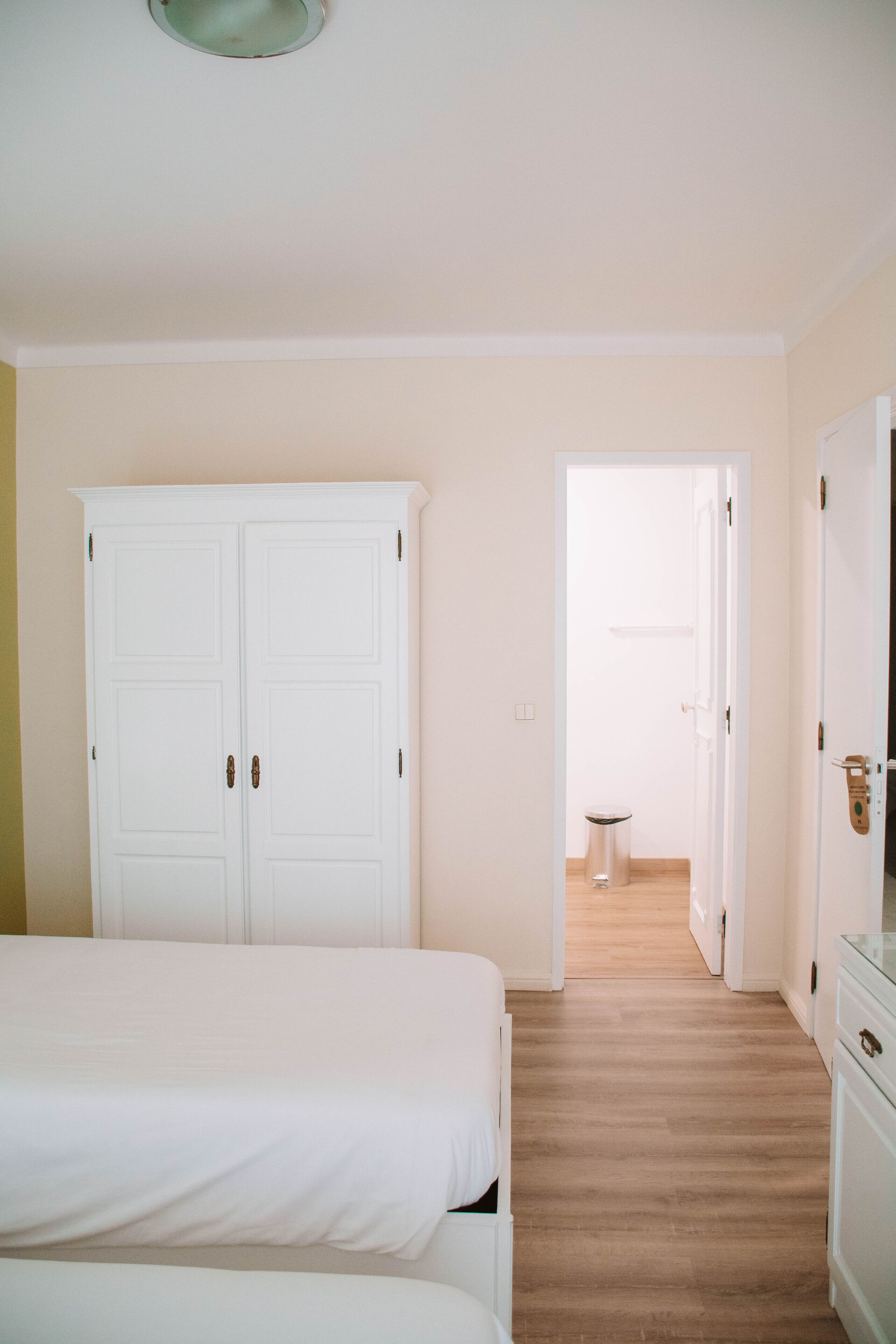 Une chambre d’hôtel avec un lit double, une armoire et une salle de bain visible à travers une porte ouverte.