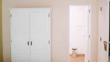 Une chambre d’hôtel avec un lit double, une armoire et une salle de bain visible à travers une porte ouverte.