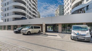 A modern building with a parking area, two white vans, and a clear sky. - Sun Towers Lux by Renters Prestige (Swinoujscie)
