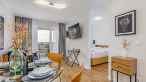 A modern hotel room with a dining area, a bed, and a TV mounted on the wall. - Sun Towers Lux by Renters Prestige (Swinoujscie)