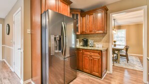 A modern kitchen with wooden cabinets, a stainless steel refrigerator, and a coffee maker on the countertop.