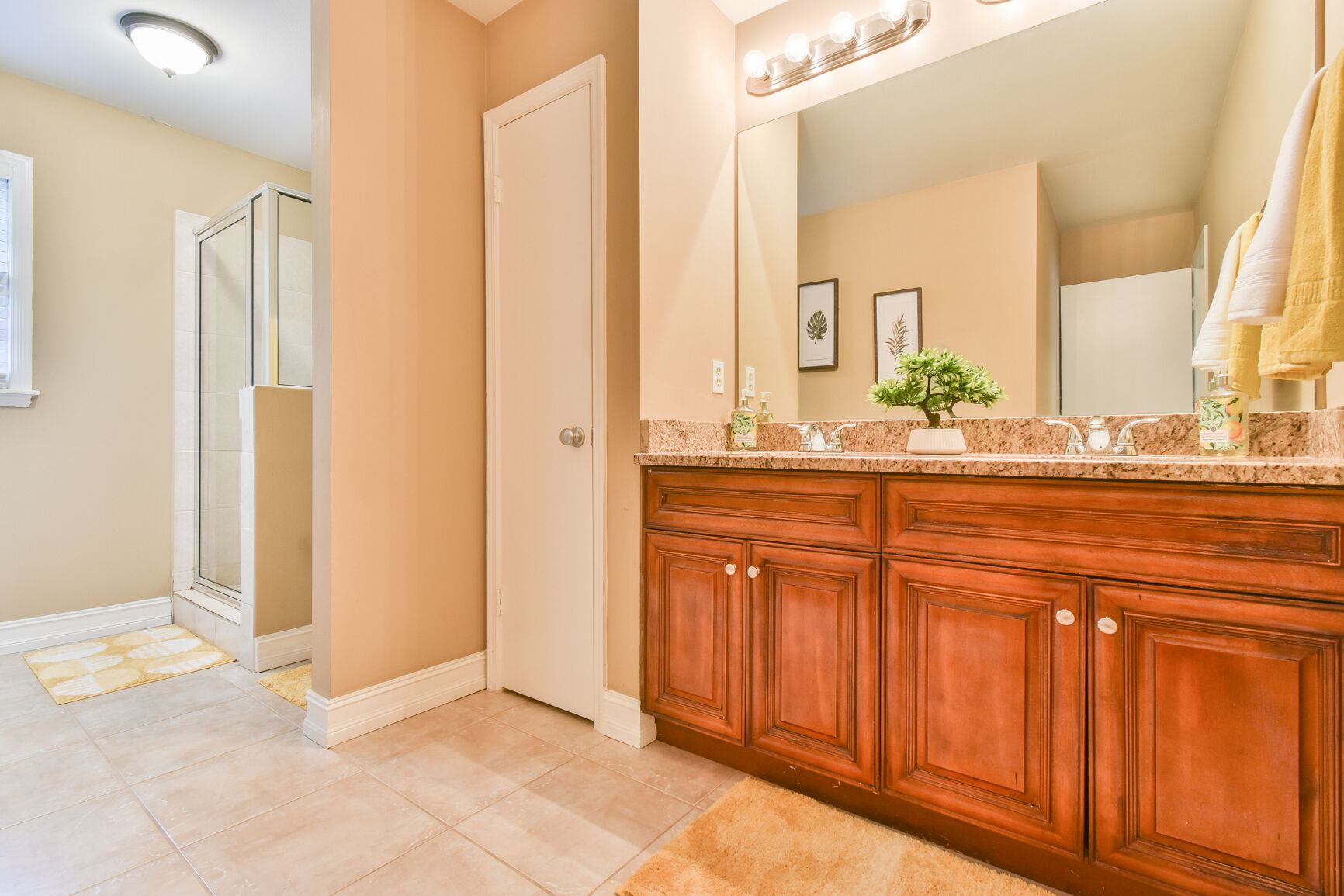 Un baño con tocador de madera, un espejo grande y zona de ducha.