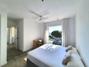 Quarto de hotel moderno com uma cama grande, uma escrivaninha e vista para o exterior.