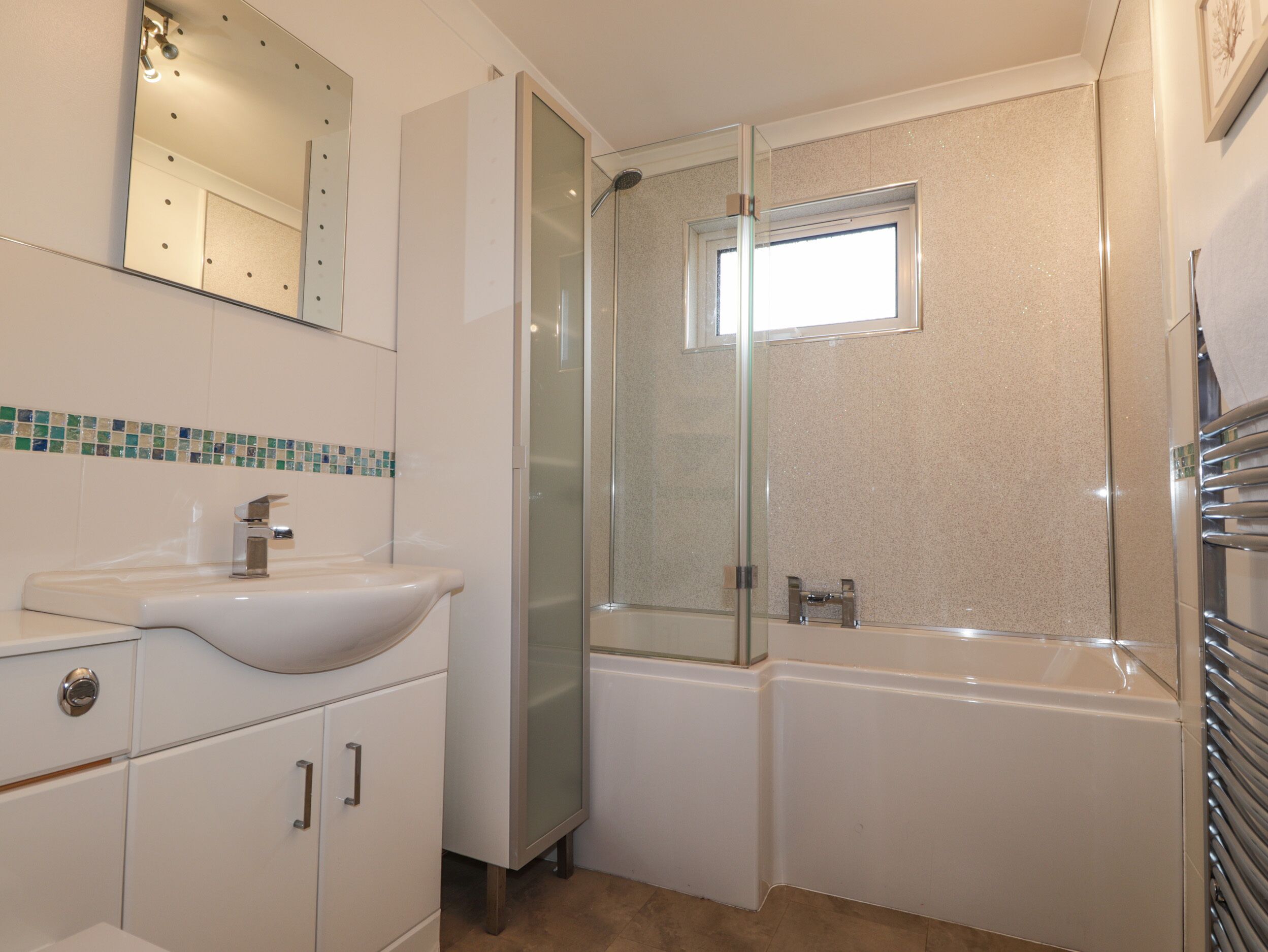 A bathroom with a white sink, a glass-enclosed shower, and a bathtub.