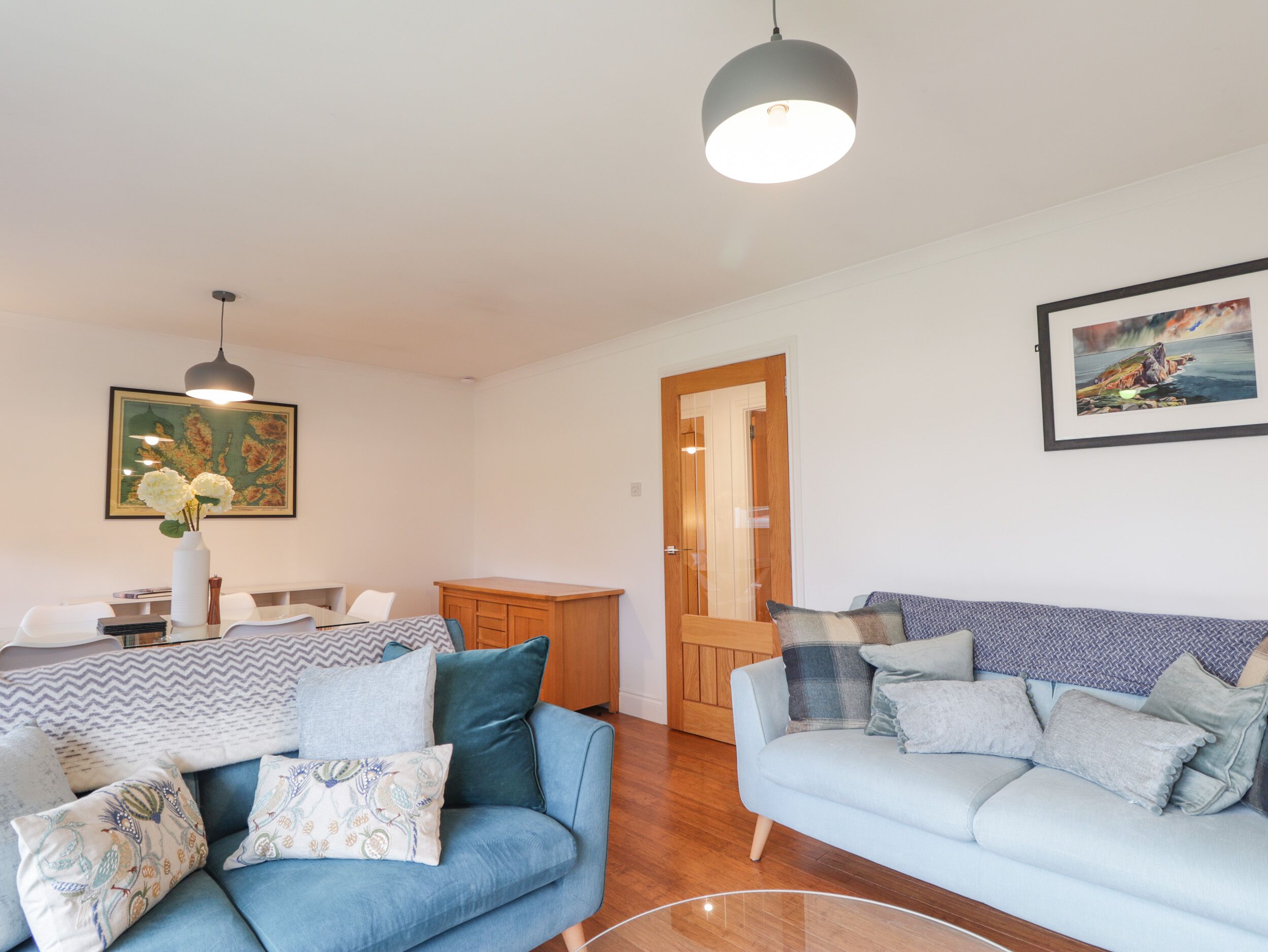Una sala de estar moderna con un sofá azul, una mesa de comedor y un mueble de madera.
