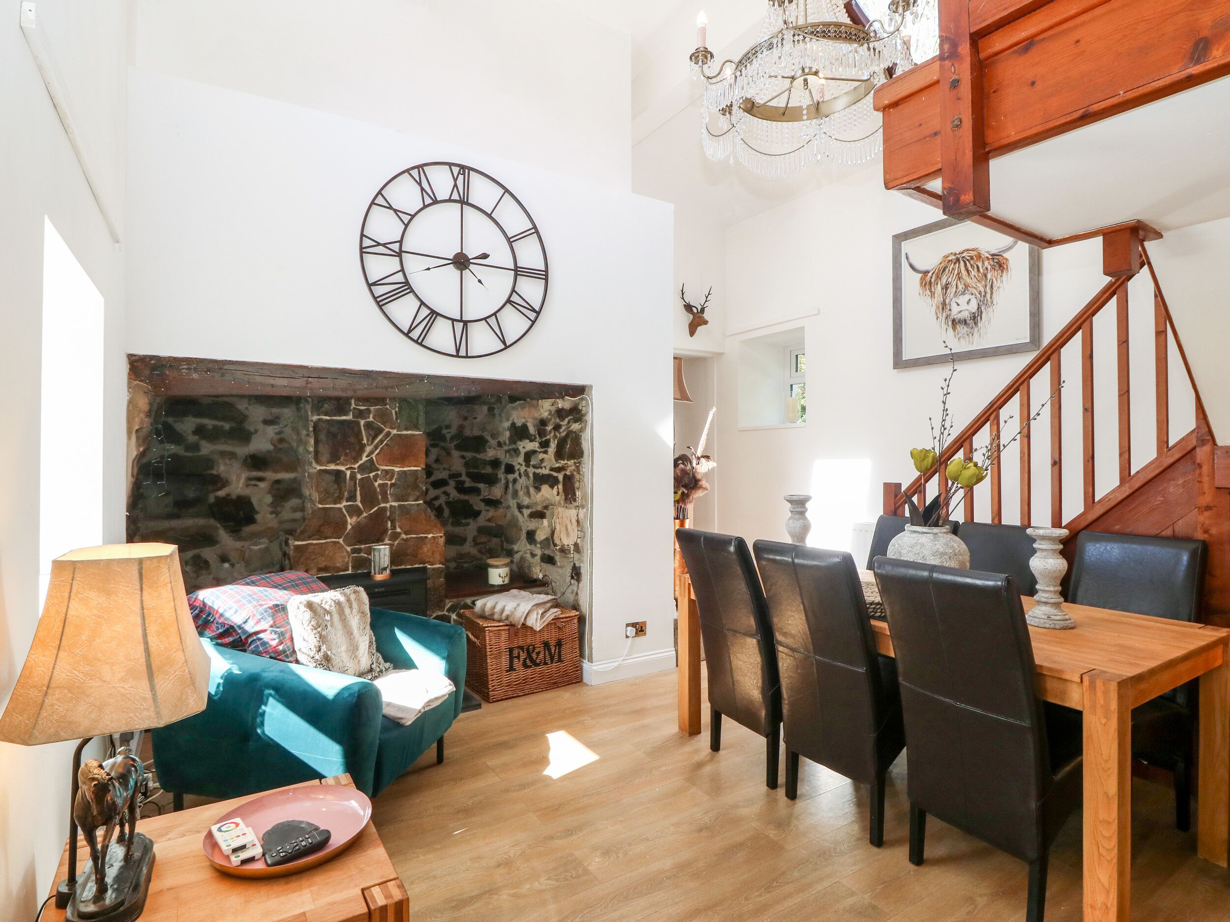 Un salon chaleureux avec une cheminée en pierre, un coin repas avec des meubles en bois et une grande horloge murale.