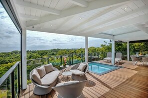 Una terraza moderna al aire libre con piscina, zona de estar y vistas al bosque.
