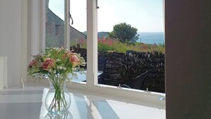 Blick durch ein Fenster, auf einem Tisch steht eine Blumenvase.