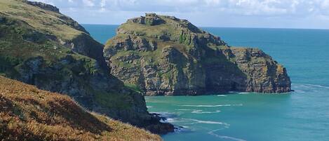 A coastal landscape with rocky cliffs and a clear view of the sea.