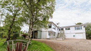 Une maison à deux étages avec une allée pavée et un porche abrité.