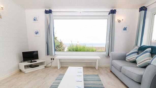 Un salon moderne avec un téléviseur à écran plat, un banc blanc, un canapé gris et un tapis à rayures.