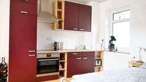 A compact kitchenette with a built-in oven, a coffee machine, and a sink.