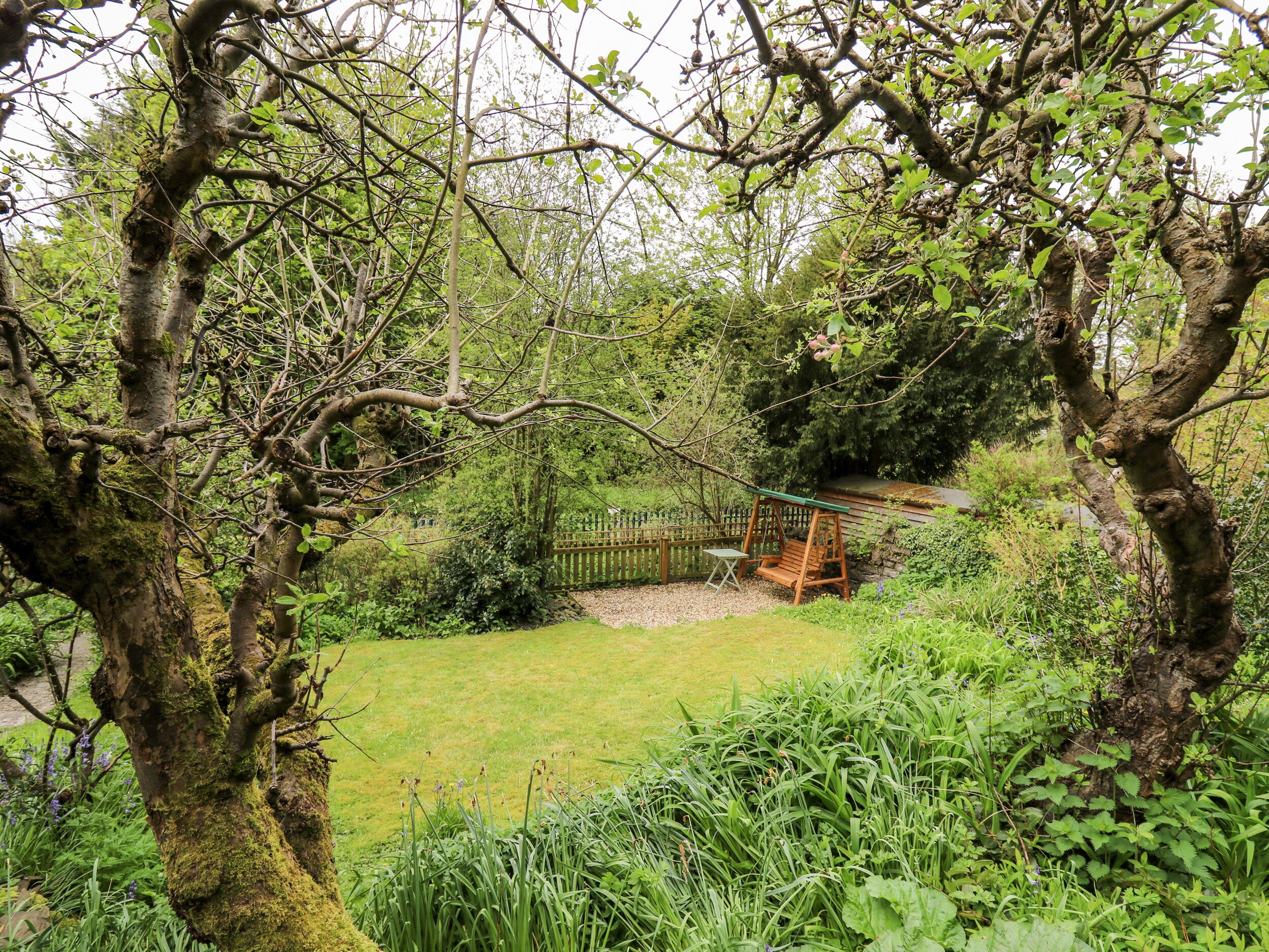 Un jardin avec une balançoire, une clôture en bois et une pelouse verdoyante.