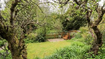 Un jardin avec une balançoire, une clôture en bois et une pelouse verdoyante.
