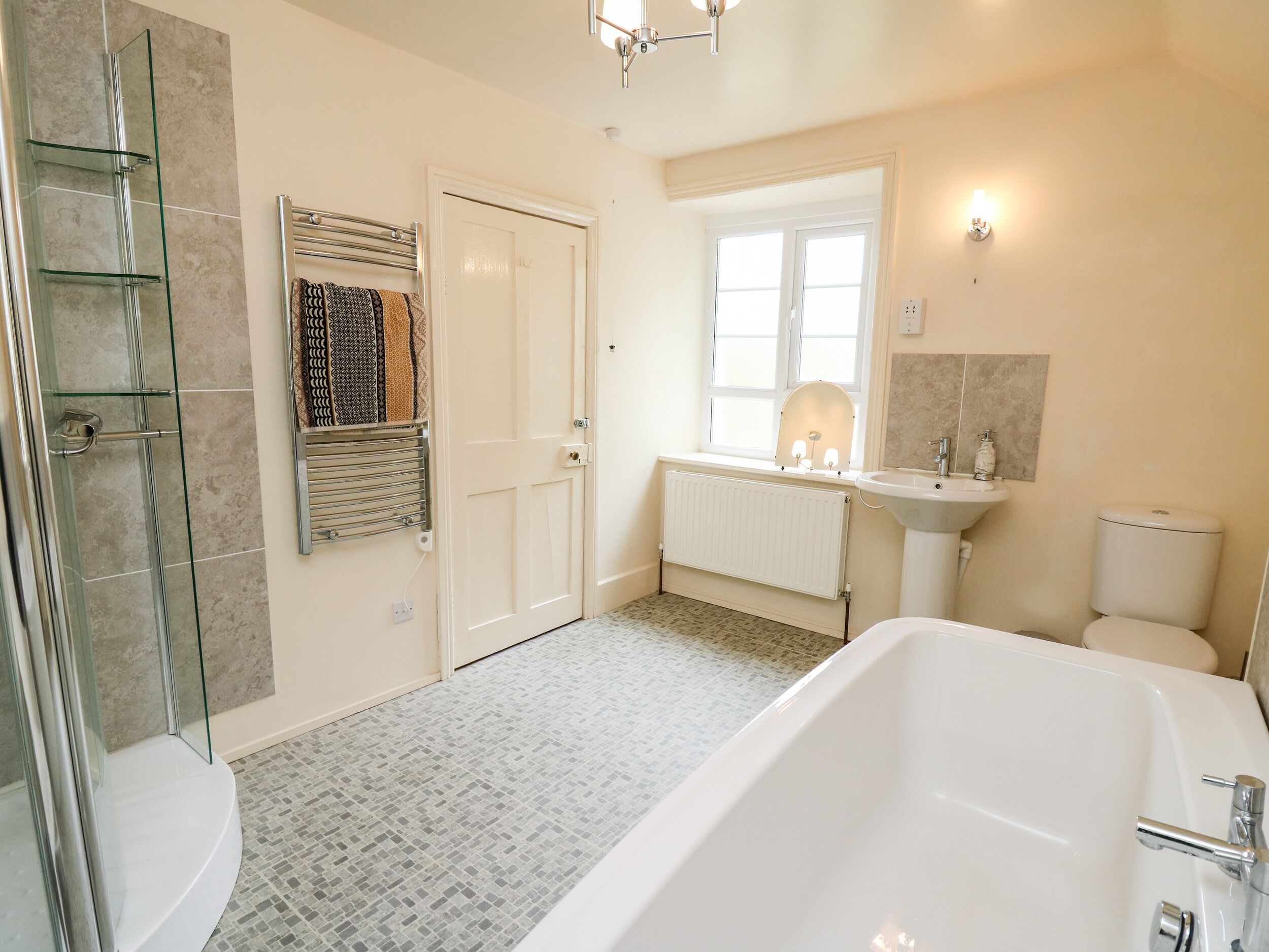 Une salle de bain avec une douche à parois de verre, une baignoire blanche, un lavabo et des toilettes.