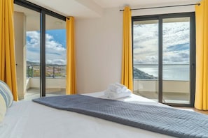 A hotel room with a bed, a view of the sea, and yellow curtains. - Banana Tree (Camara de Lobos)