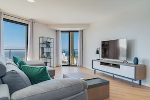 A modern living room with a sofa, TV, and balcony with a view. - Banana Tree (Camara de Lobos)