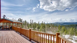 En träveranda med utsikt över en skog och berg.