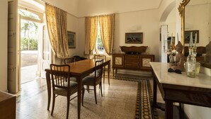 A dining area with a wooden table and chairs, a cabinet with a mirror, and a view of the outdoors through a window. - Villa Manfredi by Wonderful Italy (Fasano)