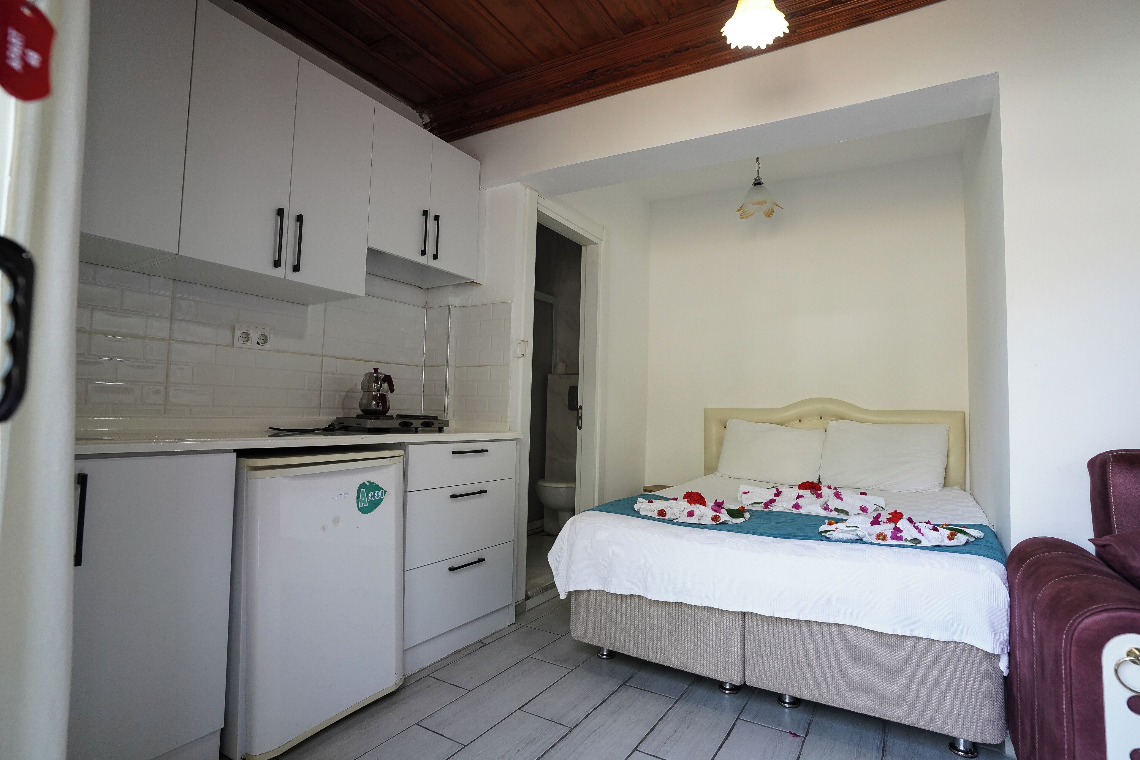 A compact room with a bed, a small kitchenette, and a bathroom.