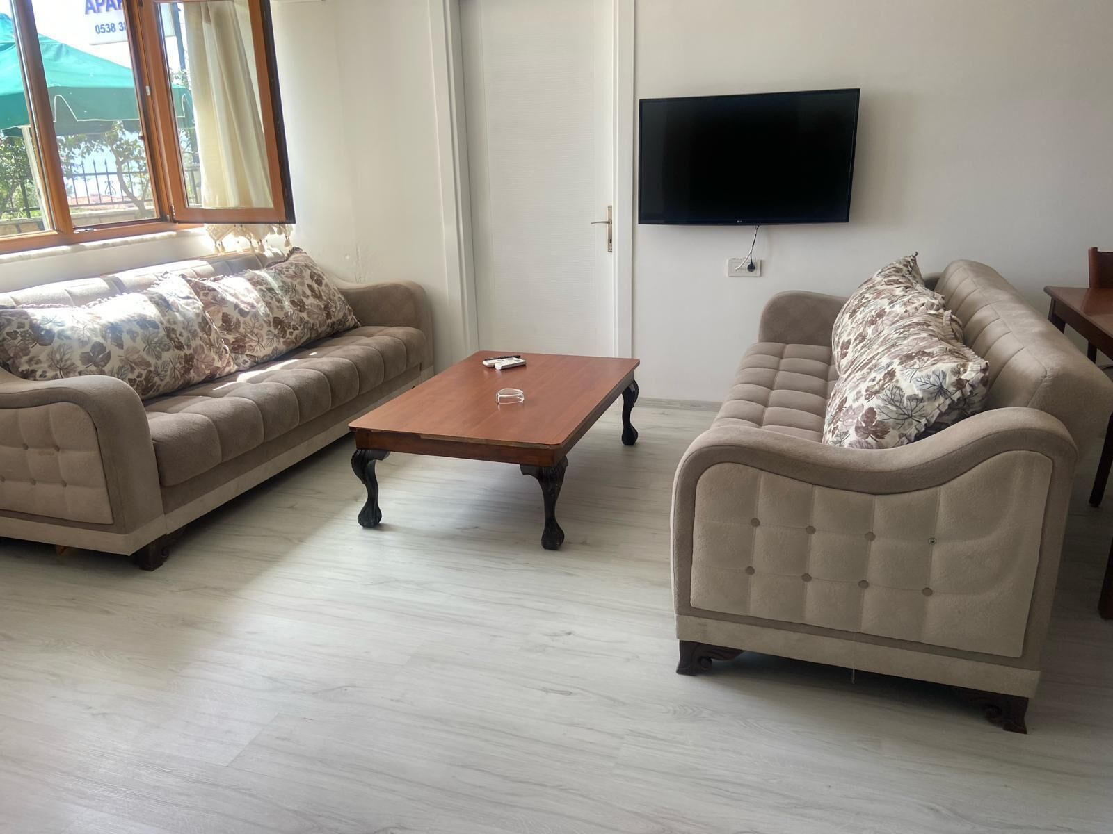 A living room with two sofas, a coffee table, and a flat-screen TV mounted on the wall.