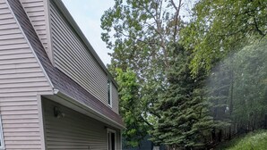 A backyard with a covered patio, a grill, and a large water heater. - Waldheim Cottage: In-town bar Harbor Hideaway (Bar Harbor)