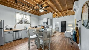 A modern kitchen with white cabinets, a dining table, and chairs. - Homely Haven Near A&M (Bryan)