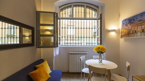 A cozy room with a blue sofa, a white table with chairs, and a large window with a view of the city. - notaMi - Voghera Fashion District (Milan)