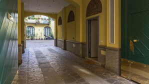 A stone-paved corridor with a green door and arched windows. - notaMi - Voghera Fashion District (Milan)