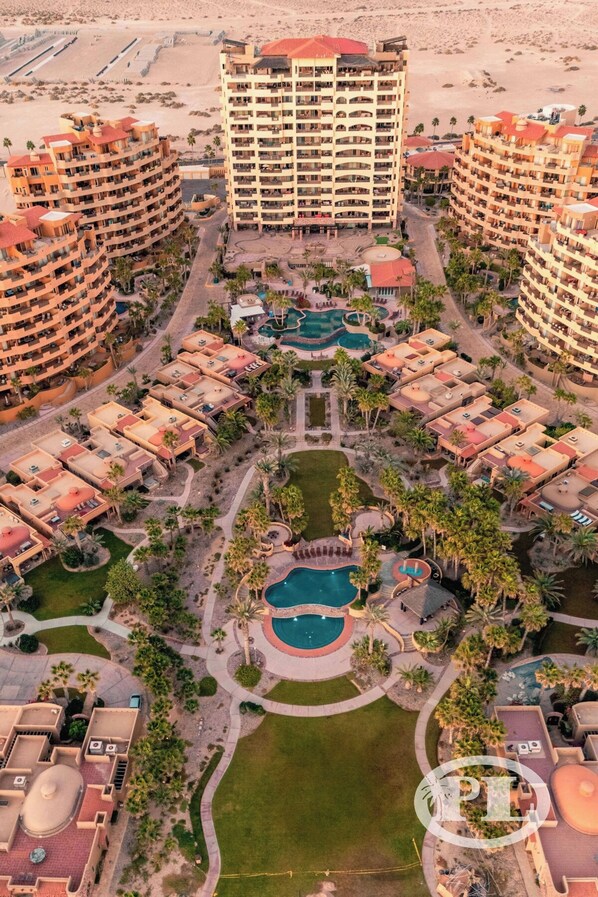 A resort with multiple buildings, a central pool area, and surrounding greenery.