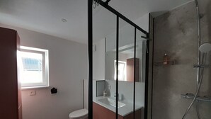 A modern bathroom with a toilet, sink, and shower.