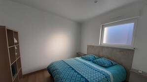 A bedroom with a bed, a window, and a wooden wardrobe.
