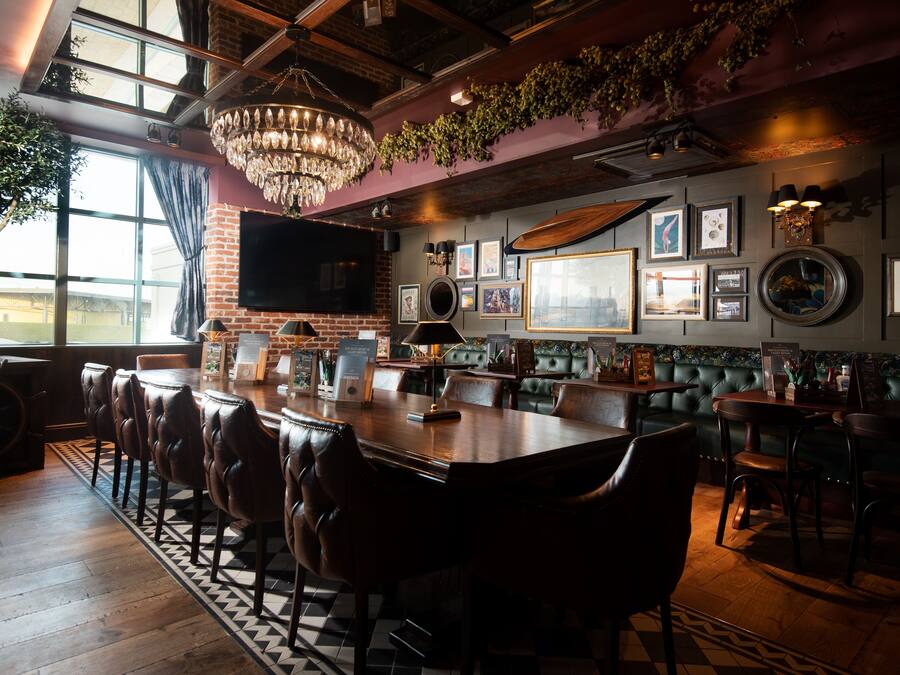 Una zona de bar con sillones de cuero, una barra de madera y una gran pantalla de televisión.