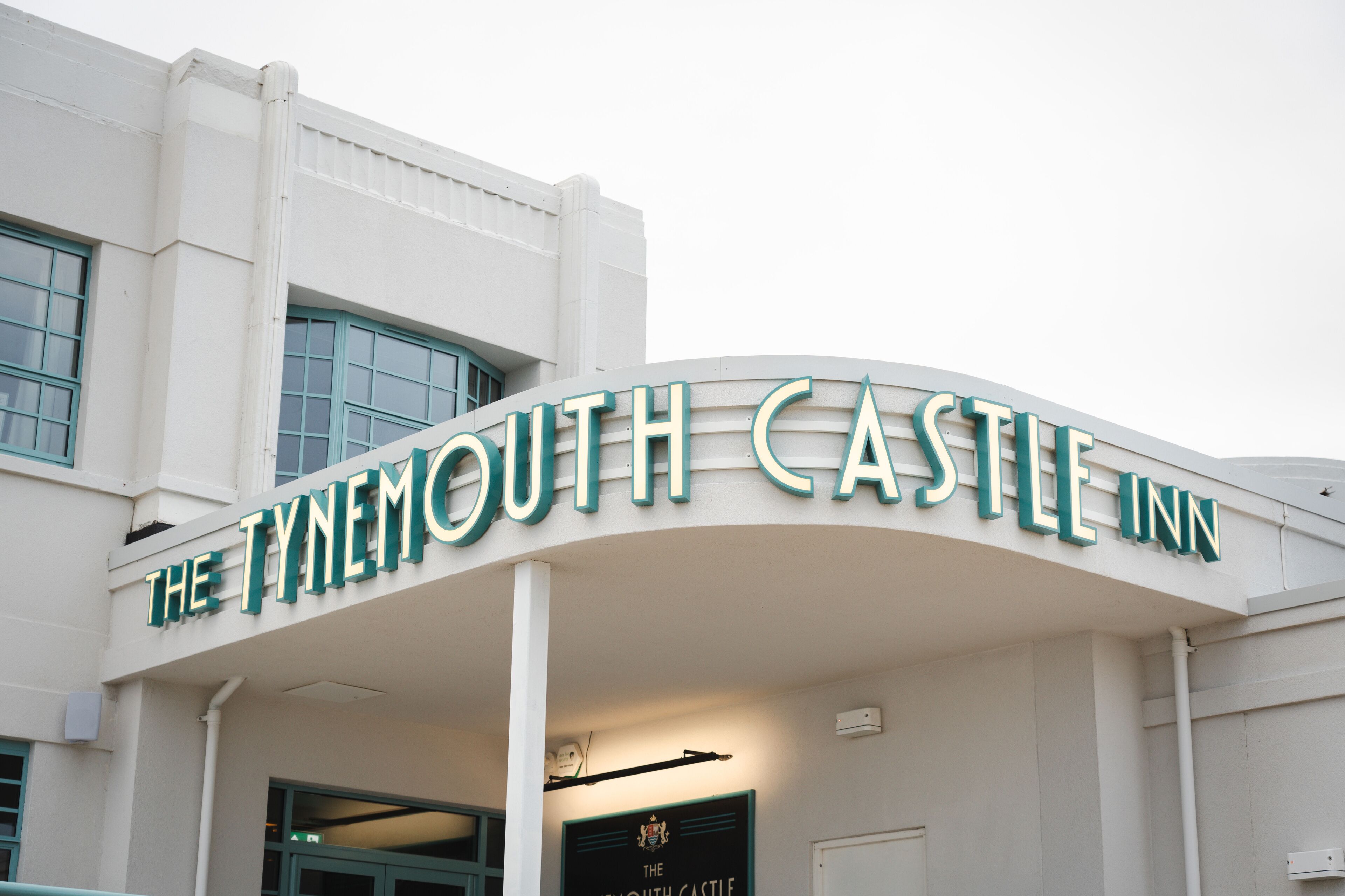 The exterior of The Tynemouth Castle Inn with a prominent curved sign.