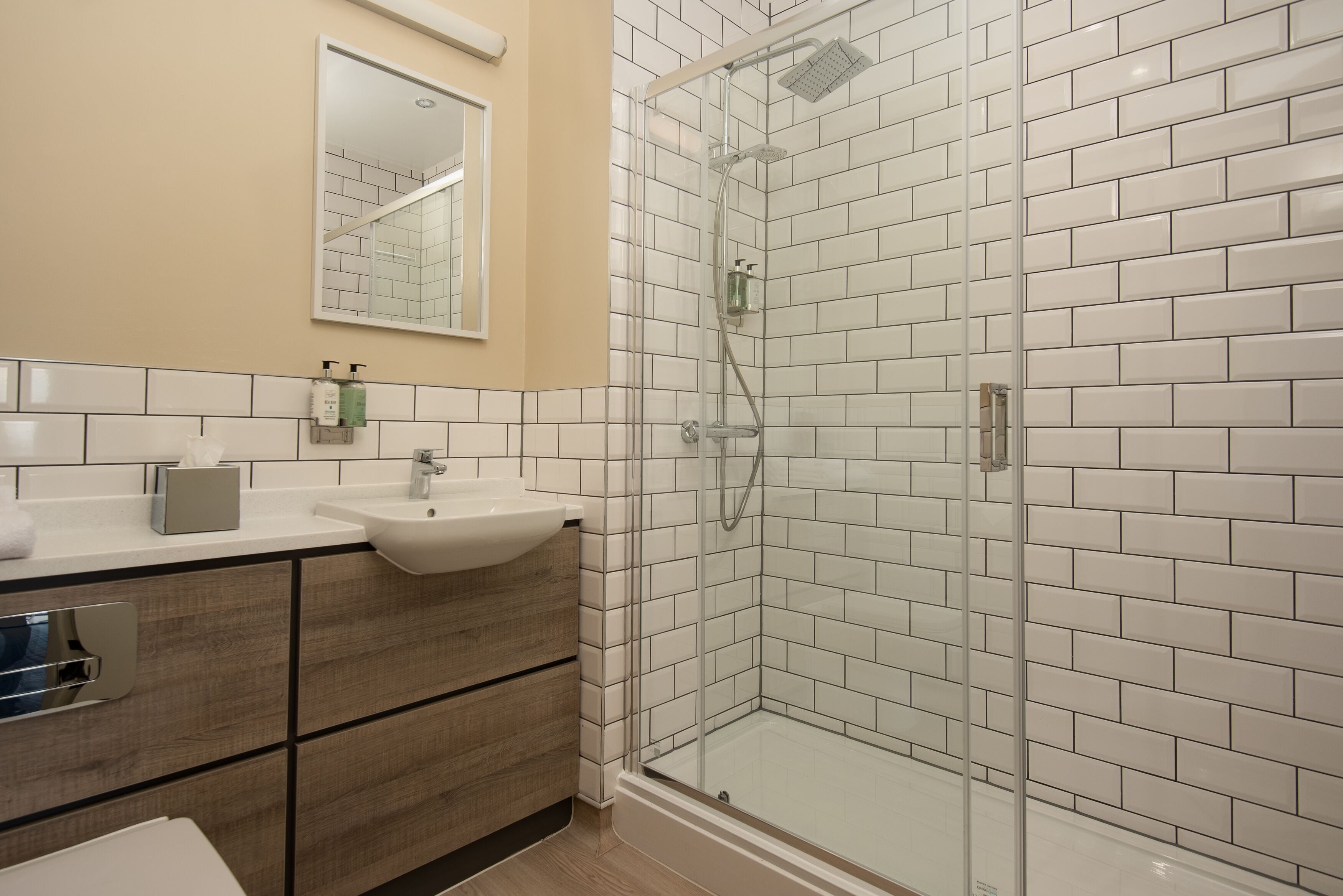 A modern bathroom with a glass-enclosed shower, a sink, and a mirror.