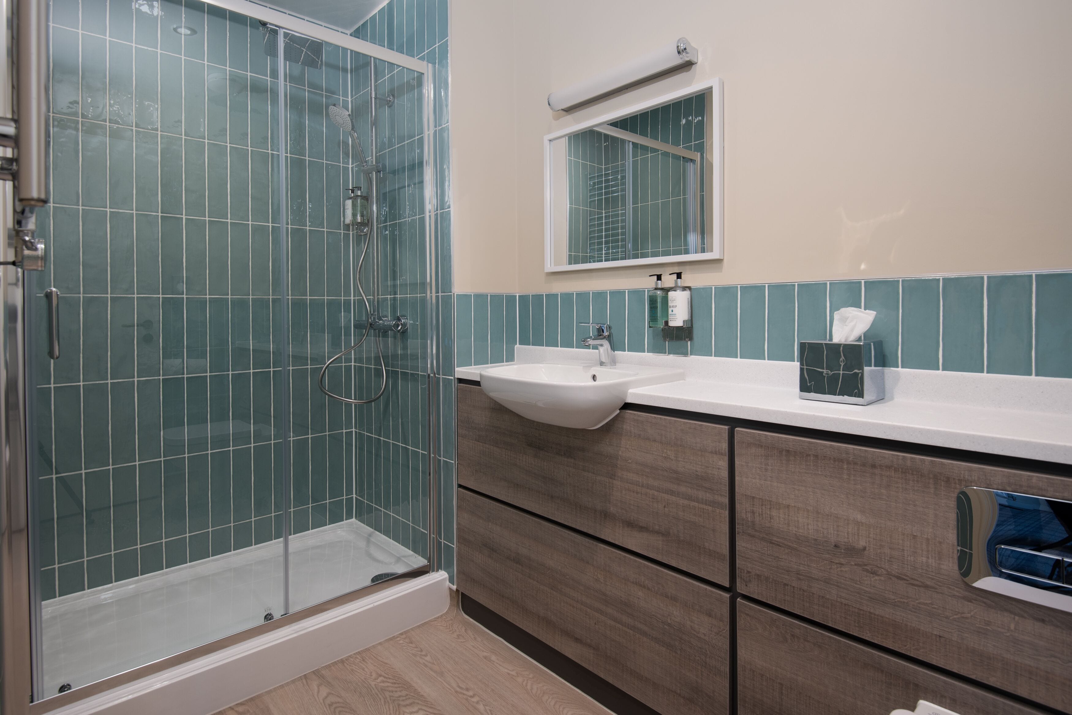 A bathroom with a glass shower enclosure, a sink, and a vanity with drawers.