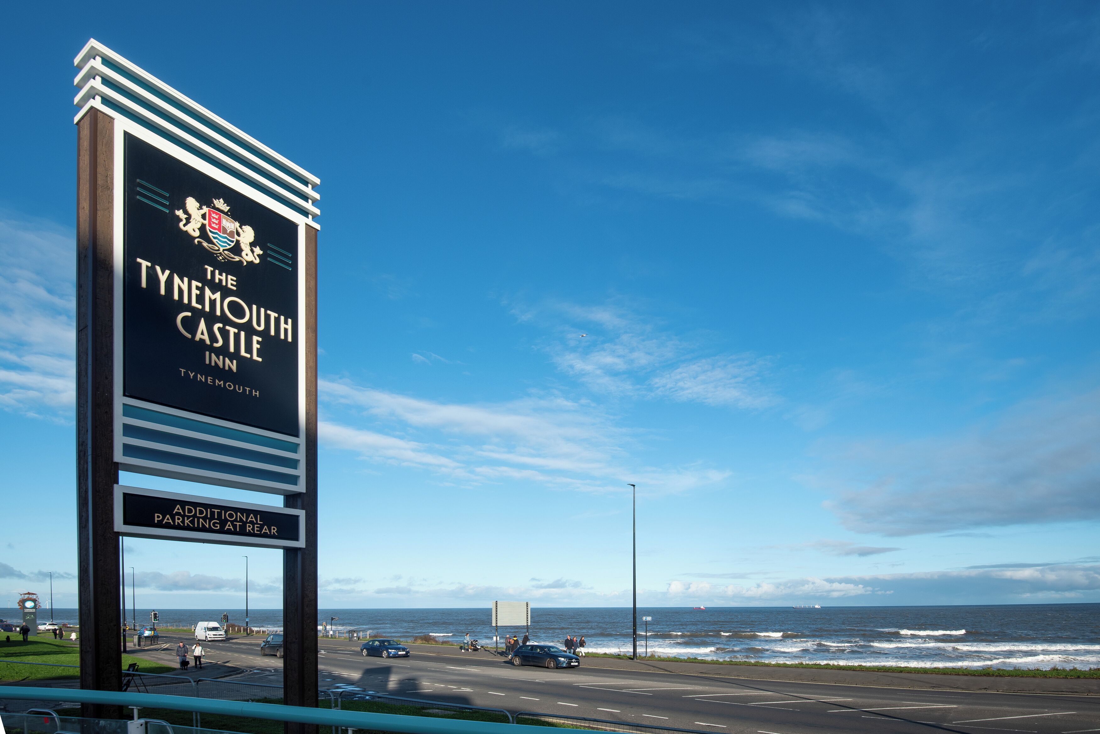 Opastekyltti, joka osoittaa Tynemouth Castle Inn -hotelliin, ja josta avautuu näkymä merelle.