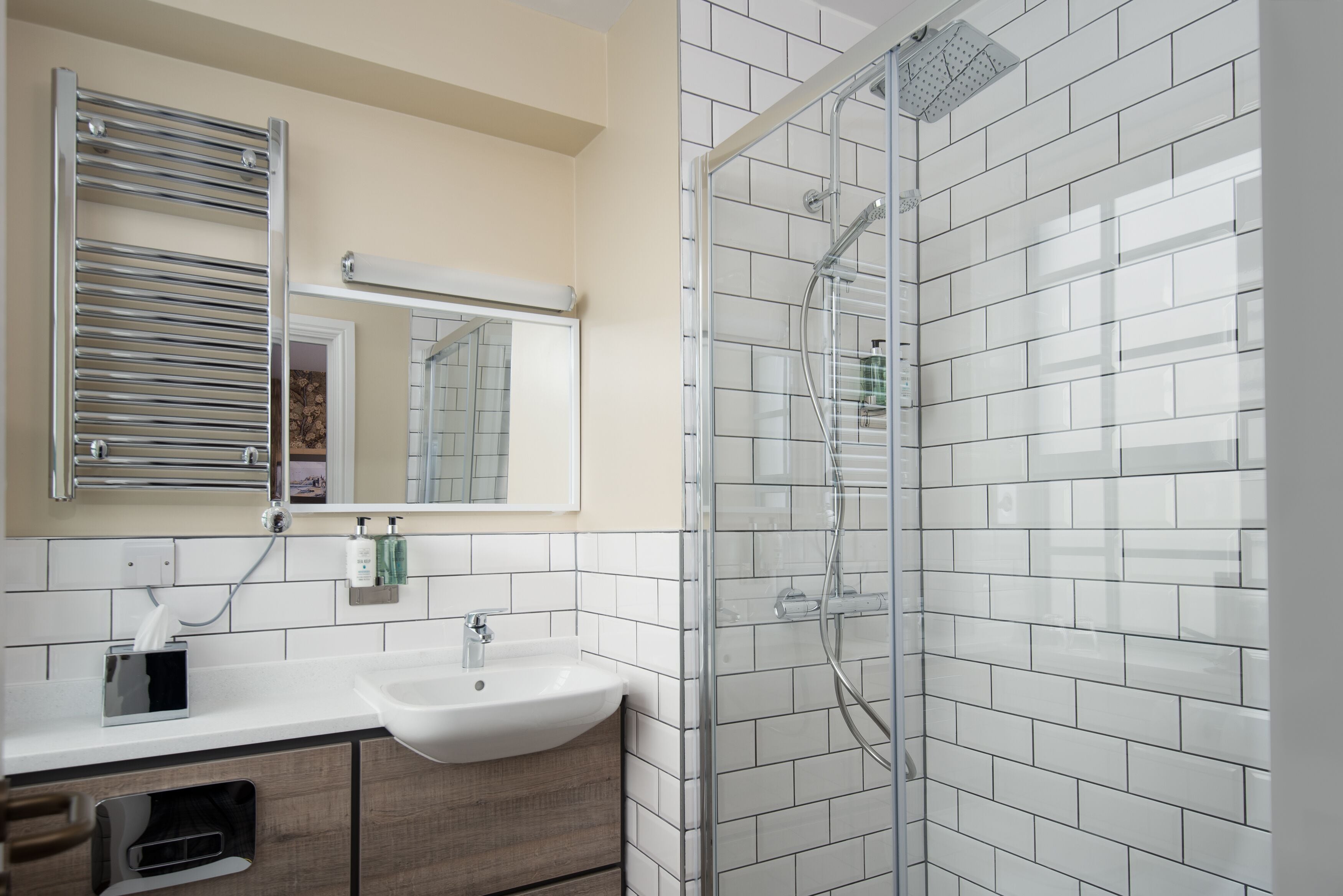 Un baño moderno con un lavabo blanco, espejo y cabina de ducha de vidrio.
