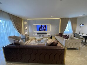 A modern living room with a flat-screen TV, comfortable seating, and a dining area. - Mastermindsluxuryliving (Lagos)