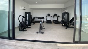 A modern gym with various exercise equipment, including treadmills, an elliptical, and free weights. - Mastermindsluxuryliving (Lagos)