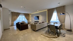 A modern living room with a sofa, a coffee table, a TV, and a dining area with chairs and a table. - Mastermindsluxuryliving (Lagos)