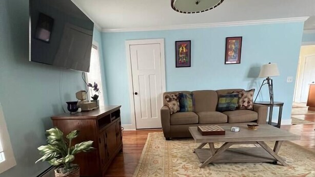 Una sala de estar con sofá, mesa de centro y televisor montado en la pared.
