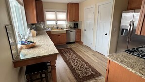 Una cocina moderna con armarios de madera, un refrigerador de acero inoxidable y una isla central con taburetes.