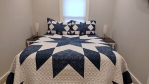 Un dormitorio con una cama grande, una mesita de noche, una lámpara y una ventana con persianas.
