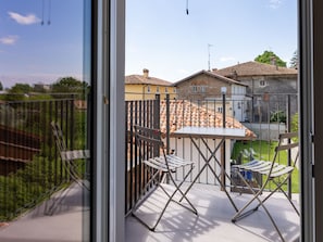 Enjoy the view of the neighborhood from this balcony with a metal railing, two chairs, and a table.